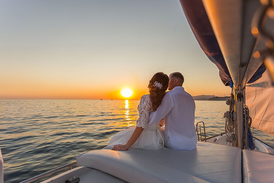 Personal Insurance - Portrait of a Newly Married Couple Sitting on a Yacht Enjoying the View of the Ocean and the Sunset