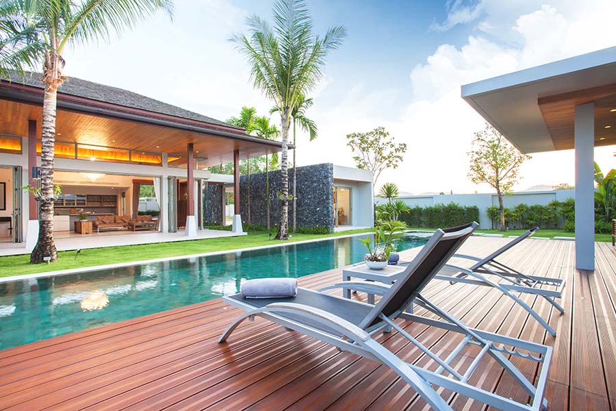 Private Client - View of a Luxury Home By the Beach with Two Palm Trees and a Pool Next to a Patio with Two Lounge Chairs